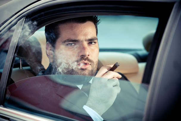 Man in the back seat of a car smoking - 写真・画像