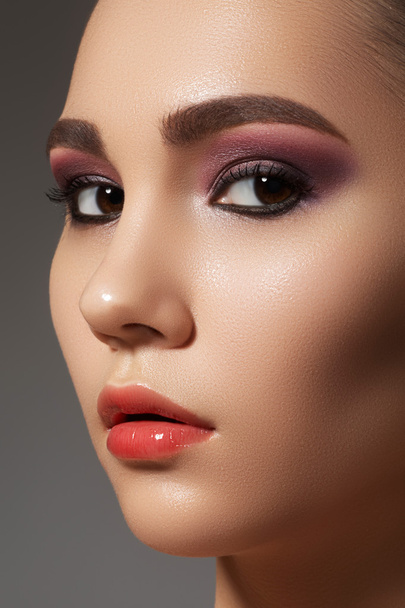 Closeup beauty portrait of attractive model face with bright visage. Purple eye makeup and gloss lips make-up - Fotó, kép