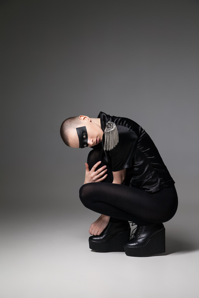 agressive bald sitting woman with mask makeup - Foto, afbeelding