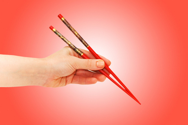Hand holding choipsticks on gradient - Foto, afbeelding