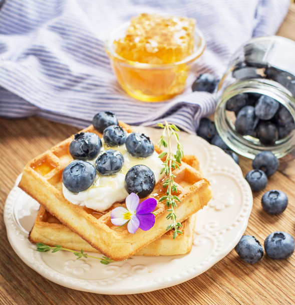 Belgian golden waffles for breakfast with fresh berries and flower honey on wooden background. The concept of home-cooked breakfast.  - Foto, Bild