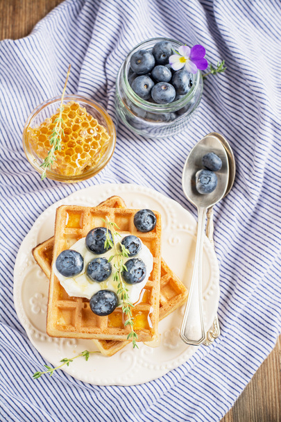 Belgian golden waffles for breakfast with fresh berries and flower honey on wooden background. The concept of home-cooked breakfast.  - 写真・画像
