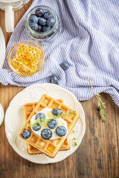 Belgian golden waffles for breakfast with fresh berries and flower honey on wooden background. The concept of home-cooked breakfast.  - Valokuva, kuva