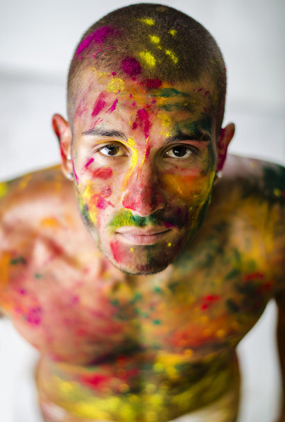 Handsome young man with skin all painted with Holi colors - Photo, image