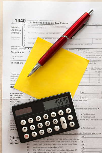 Налоговая форма, красная ручка, калькулятор и стикер
 - Фото, изображение