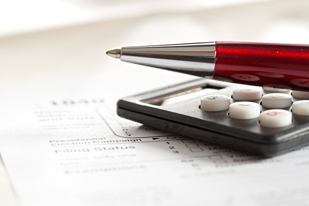 Formulário fiscal, caneta vermelha e calculadora
 - Foto, Imagem