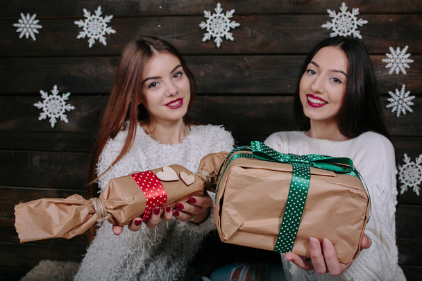 Duas meninas bonitas oferecem presentes para a câmera
 - Foto, Imagem