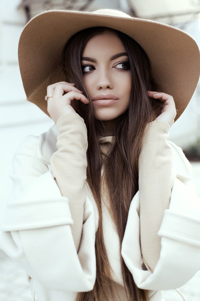 glamour girl with dark straight hair wears luxurious beige coat with elegant hat  - Fotó, kép