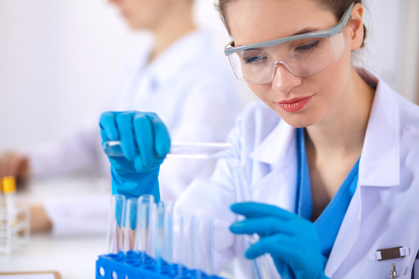 Žena vědec je obklopen lékařskými lahvičkami a baňky, izolované na bílém pozadí - Fotografie, Obrázek