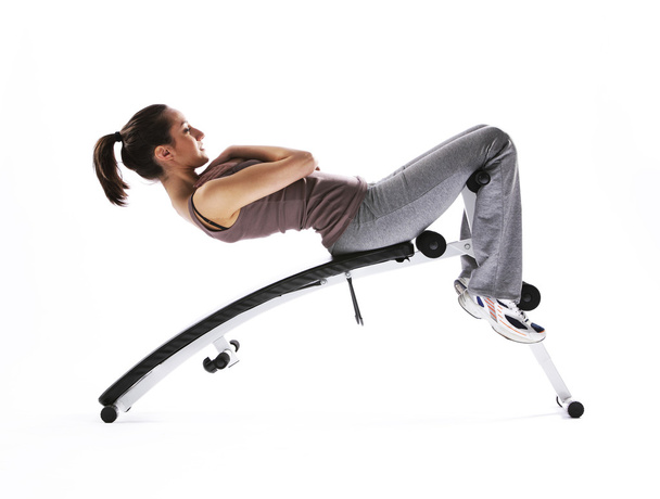 Woman using fitness machinery, white background - Foto, Bild