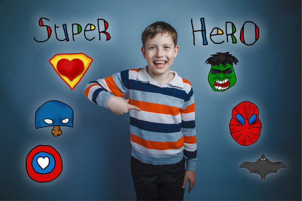 Хлопчик-підліток вказує пальцем вниз і сміється з супергеройської суперсили
 - Фото, зображення