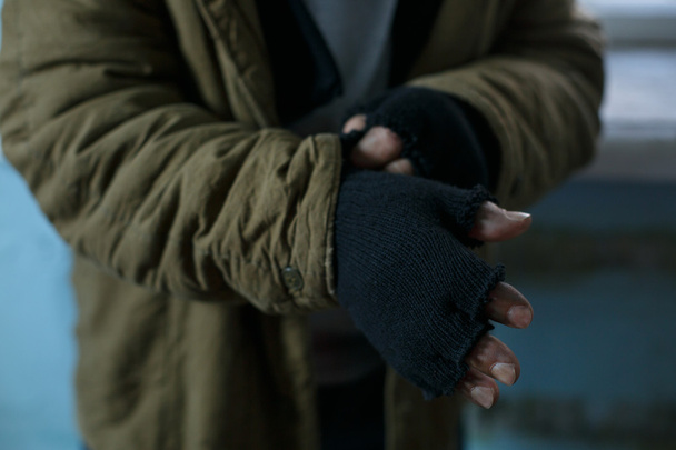 ホームレスの男性が彼の手袋を修正. - 写真・画像