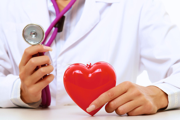 Uma médica sorridente examinando um coração vermelho
 - Foto, Imagem
