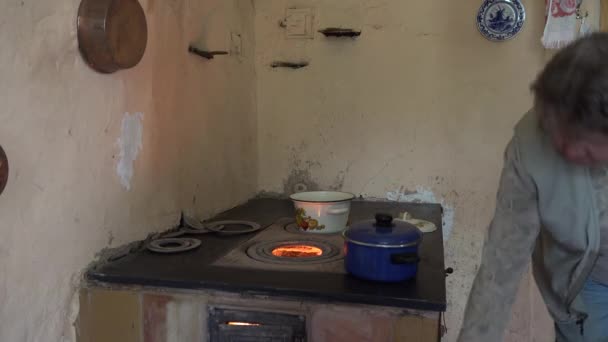 Grootmoeder vrouw koken in potten op oude oven kachel brand. 4k - Video
