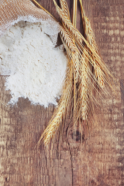 Bag of white flour with wheat ears on wooden background - Photo, Image
