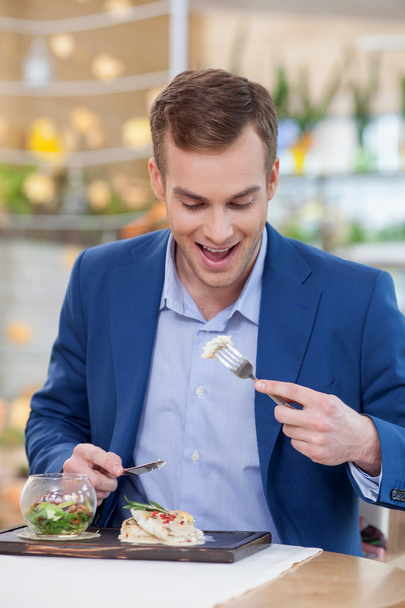 Cheerful young man is tasting food at restaurant - Foto, afbeelding