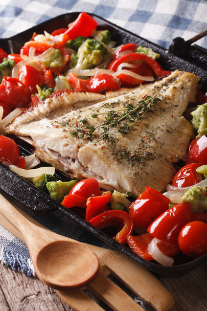 Домашняя плоская рыба с овощами крупным планом на сковороде. вертикальная
 - Фото, изображение