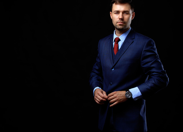 Handsome young business man standing on black background - Foto, Imagem