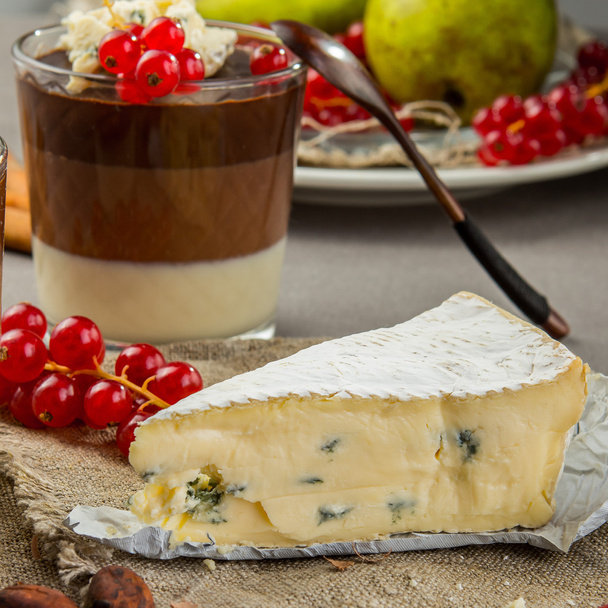Natura morta con formaggio blu, dessert al cioccolato a strati in vetro, mirtillo rosso e pera
 - Foto, immagini