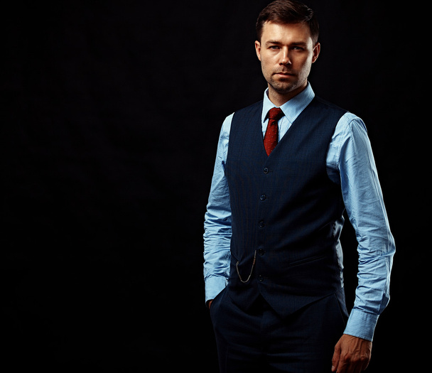 Handsome young business man standing on black background - 写真・画像