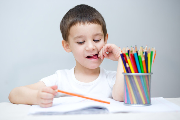 El niño sostiene lápices de colores.
 - Foto, imagen