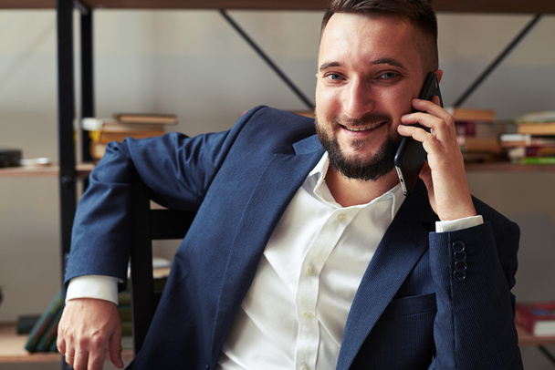 podnikatel hovoří do telefonu a usmívá se v úřadu - Fotografie, Obrázek