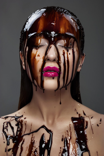 bela jovem morena mulher com chocolate fluindo no rosto
 - Foto, Imagem