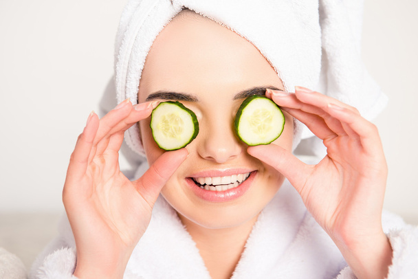 Nice young woman with cucumbers on eyes and towel on her head - Foto, imagen