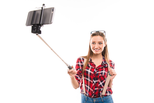 Long-haired girl with selfie stick taking photo - Fotó, kép