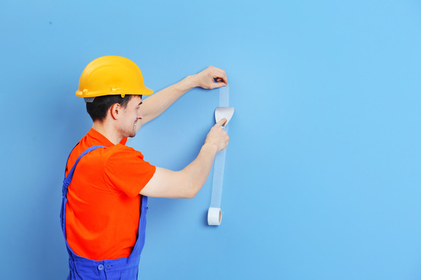 Young worker renewing apartment on wall background - Photo, image