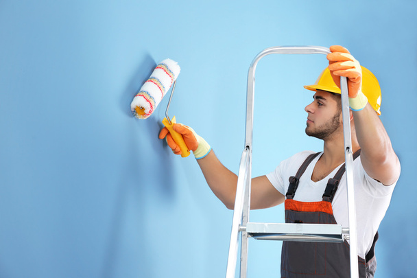 Young worker renewing apartment on wall background - Foto, Bild