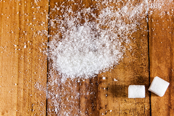 Derrame de azúcar blanco granulado sobre fondo de madera
 - Foto, Imagen