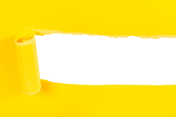 πάνω από την άποψη του κίτρινου έλασης-up σχισμένου χαρτιού σε λευκό - Φωτογραφία, εικόνα