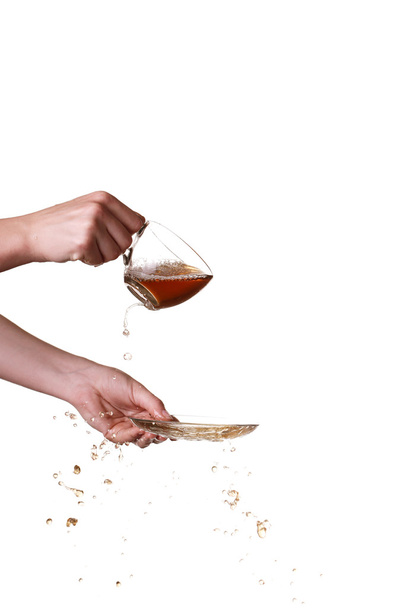 Brown splashes out drink from glass on a white background. - Photo, Image