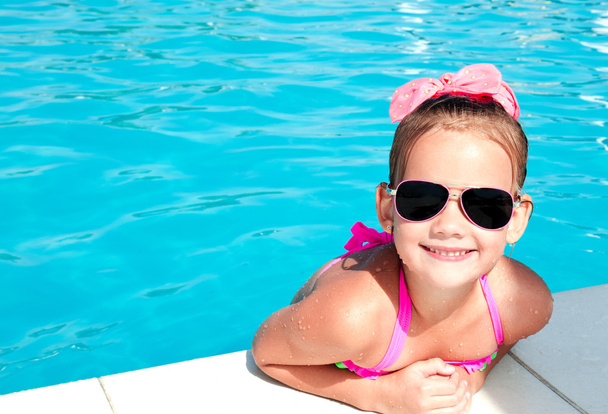 Cute smiling little girl in swimming pool - Фото, изображение