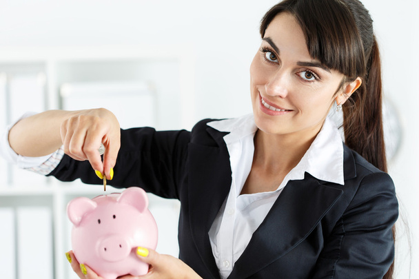 Szczęśliwy, piękna kobieta wprowadzenie pin pieniądze monety do różowy piggyban - Zdjęcie, obraz