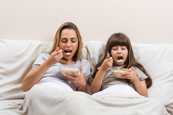 mother and daughter eating breakfast - Foto, afbeelding