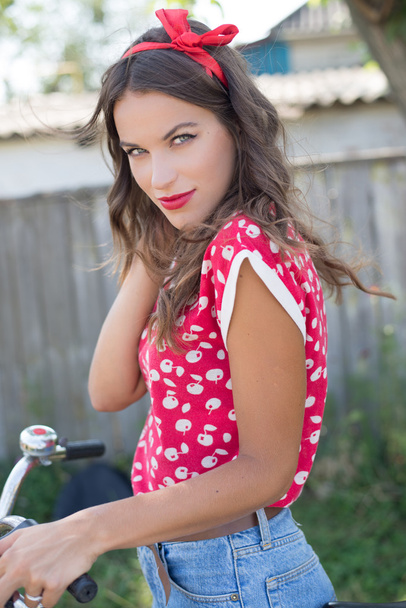 Young beautiful pinup woman cycling in countryside - 写真・画像