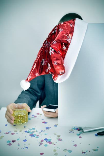 homme avec un verre d'alcool et un chapeau de Père Noël dans son bureau
 - Photo, image