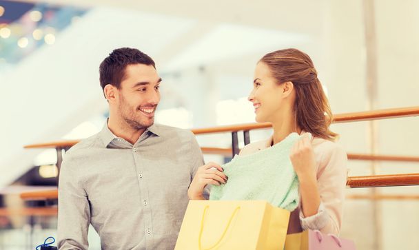 happy young couple with shopping bags in mall - 写真・画像