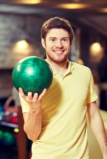 happy young man holding ball in bowling club - Photo, Image