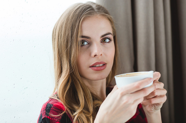 Portrait of attractive peaceful young female  drinking coffee at home - Foto, afbeelding