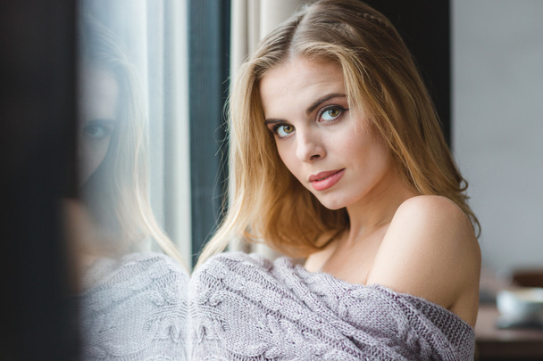 Attractive sensual woman wrapped in knitted coverlet near the window - Fotoğraf, Görsel