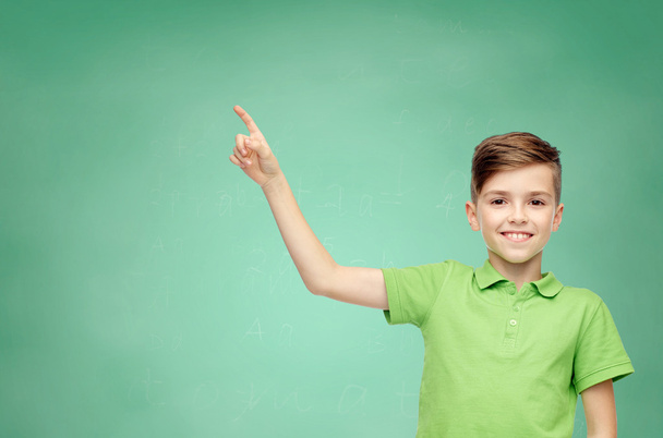 happy boy in green polo t-shirt pointing finger up - 写真・画像