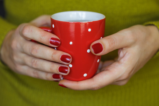 Woman hands holding a cozy red mug - Fotó, kép