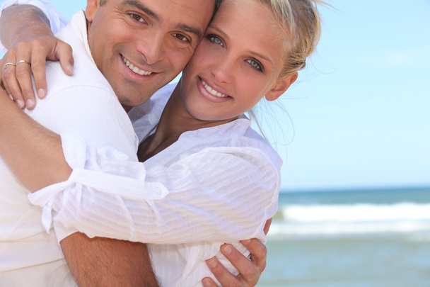 Para przytulająca się na plaży - Zdjęcie, obraz