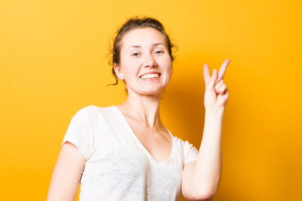 брюнетка красива дівчина показує два пальці, знак миру
 - Фото, зображення