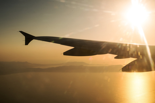 Φτερό ενός αεροπλάνου στο ηλιοβασίλεμα, η θέα από το παράθυρο. - Φωτογραφία, εικόνα