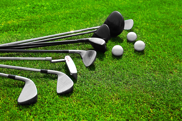 Diferentes palos de golf en una fila y bolas en una hierba verde
 - Foto, imagen