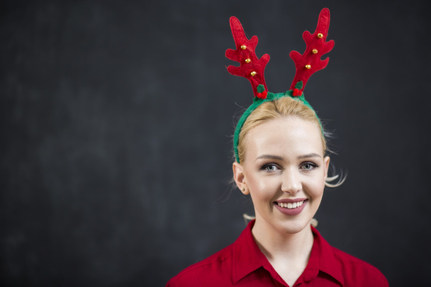 Pretty blond woman in a red reindeer Hat with a merry smile look - Valokuva, kuva
